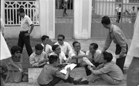 A group of students sitting and talking on the sidewalk.