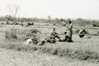 American soldiers setting up a camp in an open field.