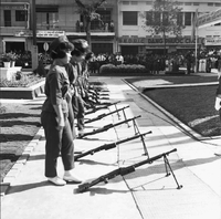 Original caption: "Mne. Nhu + Paramilit. Graduation - 27 Feb 63" Several Vietnamese women are standing in line behind their guns.
