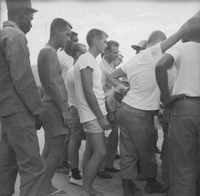 A group of American men are gathered around something off camera.