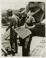 Original title: "So, Dad's an Admiral!"  "Navy Seabee Bill Stoffle takes time out at Chu Lai, South Vietnam to catch up on reading -- especially the item about his father being recently nominated to rank of Rear Admiral in the Coast Guard Reserve by President Johnson. The elder Soffle was the commanding officer of a Coast Guard Seabee battalion in the Pacific during World War II. Young Stoffle, who now serves in Naval Mobile construction Battalion SEVENTY ONE, recently received a promotion, too -- to the rating of Builder Third Class. This year, the Seabees are observing their 25th anniversary." Seabee stops work to read the news. More Seabees are in the background pouring concrete. Seabees news release 28-67 (50).