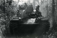 "Suoi Da, Vietnam - Headed back to their battlefield base camp near this South Vietnamese village, M48 tankers of 34th Armor give a lift to a base camp-bound infantry squad. The tankers and their ground-trooping passengers are taking part in Operation 'Junction City,' the U.S. Army's multi-division sweep of War Zone 'C.' More than 1,100 enemy have been killed so far during the hard-hitting Army sweep and clear operation." American soldiers sitting on top of a tank driving through the jungle.