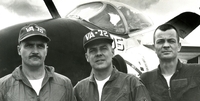 "USS Independence pilots who destroyed a North Vietnamese portable surface-to-air sight gather in front of their aircraft today. They are (left to right) Lieutenant Commander C.E. Garber of Mount Crawford, Virginia Commander Harry B. Southworth of Mexico, New York, and Lieutenant (Junior Crade) Ken Jones of Kirksville, Missouri." Portrait of three US airmen standing in front of an airplane.