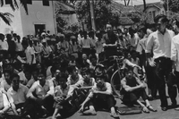 "Students wrecking min. of info." Students sitting or standing. A handful of officers can be seen in the back, making their way to the front of the crowd.