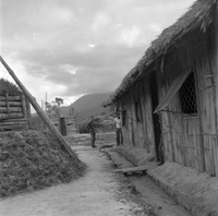 "Ashau II", grass houses and some soldier standing in front of them, taken from the side