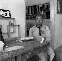 "Ai Lam - HK*" Man poses for a picture as he carves a small statue. His uniform suggests he is a prisoner.