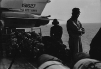 "7th Fleet" An American man wearing a headset and two other men near what may be artillery on the USS Kitty Hawk.