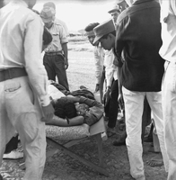 "Ca Mau" Several Vietnamese people surround someone laying on a cot.