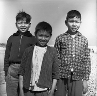 "Macau" Three young boys pose for a photogragh together, smiling.