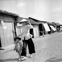 A woman is walking with her child down a village road.