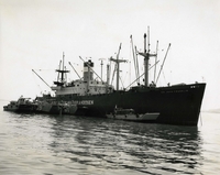 "Cargo Offloading - LCU's (Landing Craft Utility) and LCM's 8's (Landing Craft Medium) tied-up alongside merchant vessel load-up with combat cargo. These craft make numerous shuttles a day during the 24-hour, seven-days-a-week operation." Four American Navy cargo barges are pulled up alongside a large ship.