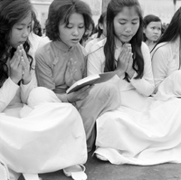 Original title: "VN Life", a group of women sitting on the group praying. The woman sitting in the center is holding a book that the other women are reading from. The photo is of a Buddhist religious service, which may have been part of the anti-Diem Buddhist Crisis protests.
