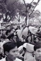 A crowd of Vietnamese people holding flags and banners. They have both American and South Vietnamese flags.
