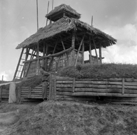 "Ashau II", a grass house with a soldier standing in front of it, teken from a below view