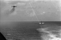 "7th Fleet" A view of the open ocean. An aircraft carrier and an ascending plane can be seen in the background.
