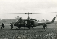 "Phuoc Tuy Province, Vietnam - Paratroopers of the 173rd Airborne Brigade dash from helicopters of the 82nd Aviation Battalion during the air assault phase of recent search and destroy operations in Phuoc Tuy Province." Four American soldiers disembark from a helicopter in an open field. There is another helicopter in the background.