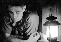 An American soldier is sitting near a lantern.