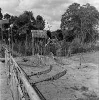 "Montagnards - Showplace Strat. Ham - 8-21-62 - In MTs - Faces - Blockhouses" A fence and garden, covered in wooden decoractions.