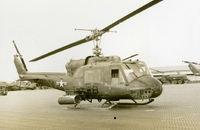 "The UH1E 'Huey' is s jet turbine helicopter, designed for utility use. A Gunship version supplies close air support." A US Marine Corps helicopter sitting in an airfield. (damaged)