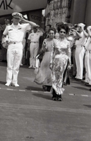 Nguyá»…n Thá»‹ Mai Anh and another Vietnamese woman walk past a group of saluting American officers and sailors. They are onboard a US Navy 7th Fleet ship.