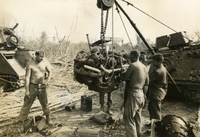 "Minh Than, Vietnam - A U.S. Army maintenance crew 'pull the pack' from one of their track vehicles during operation 'Junction City II.' The engine is from a M113 Armored Personnel Carrier and the soldiers are from 2/22nd Mechanized Infantry, 4th infantry Division." American soldiers stand around an engine winched up on a small crane. There are two tanks in the background.