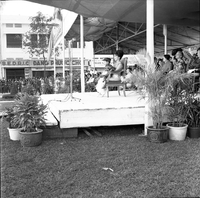 Original caption: "Mne. Nhu + Paramilit. Graduation - 27 Feb 63" Madame Nhu is sitting on stage with a young boy in her lap.