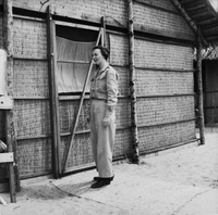An American woman has her photo taken as she stands next to a wicker hut.