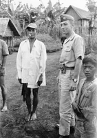 A soldier poses next to a couple villagers.