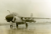 "An A6A 'Intruder' is a two seat jet, high altitude attack bomber, capable of carrying a heavy load of conventional weapons." A US Marine Corps jet sitting in a rainy airfield.