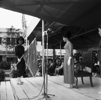 Original caption: "Mne. Nhu + Paramilit. Graduation - 27 Feb 63" Madame Nhu (Tran Le Xuan) is standing as a women holding a flag is front of her.
