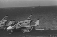 "7th Fleet" Navy airplanes sitting on an aircraft carrier in open water. A second aircraft carrier can be seen in the background.