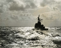 "The USS Collett heads across the Tonkin Gulf at high speed after taking on a fresh supply of ammunition." A naval ship sails across open water away from the camera.