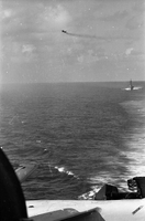 "7th Fleet" A view of the open ocean. An aircraft carrier and an ascending plane can be seen in the background. Photo taken from a second aircraft carrier.