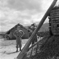 "Ashau-Laos Border", 2 soldier standing in between "grass houses?"