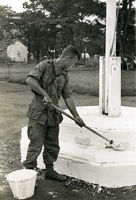 "Pleiku, Vietnam (Army IO) - PFC Michael Sweck of Crestview, Fla., takes care of painting the flag pole during the renovation of the sector girl's school here which was closed for several months because of damages. PFC Sweck is a member of the Army's 173rd Airborne Brigade." An American soldier paints a platform with a flagpole on top.