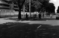 "Unidentified", Vietnamese soldiers or police set up barbed wire blockades on a sidewalk, probably to counter civilian protesters. Cars and motorcycles drive down the street.