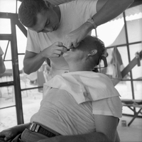 An American man has his teeth examined by another in a medical tent.