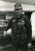 "Carrier Air Wing Nine Aviators pounded the KEP Airfield 37 miles Northeast of Hanoi, this morning. Their bombs destroyed four MIG's parked in ground revetments. Strike leader CDR. J. Andrew Burnett, of Jacksonville, Florida, executive officer of attack squadron 113 from the USS Enterprise, complimented the group's performance he said 'It was the prettiest job in a major strike I've seen. The section leaders, the wingman...everybody... did a perfect job.' A4 Skyhawks From his squadron served both as flak suppressors and as bombers." An American Navy pilot in uniform walks toward the camera.