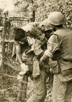 American soldier is standing in some body of water, and empties water from his helmet. The water obscures the soldiers face.