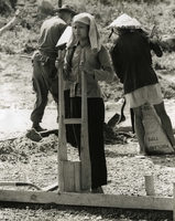 "Women make up the work force that labor beside Seabee Murphy in Tan Hy, the village's men-folk are in the fields or aboard their fishing sampans. The 'tamper' this woman is using is using to compress the foundation soil is common to all construction - this one was made and is manned by Vietnamese." Vietnamese workers mixing concrete on a build site.