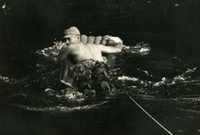 "Khanh Duong, Vietnam - Sgt. Ramon Thomas, 1st Brigade, 101st Airborne Division, crosses a jungle stream by air mattress moments after a brief firefight with the Viet Cong during Operation Summerall. The enemy, however, escaped through a series of tunnels on the other side of the stream, Sgt. Thomas learned later." An American soldier in the water. He is holding an inflated raft and a rope is tied around his waist.