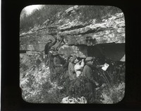 Original caption:  Ledge formerly quarried at Green's exposure in lower part of bluffs opp. So. Bend. NAB. Oct 21, 1911 Group of men viewing and stand beneath ledge. Cass County. (121111-00246)