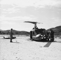 American soldiers standing around around a crashed Army helicopter.