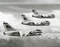 "Three of the Navy's new A-7A Corsair II attack aircraft from Attack Squadron 147 flying in formation." Three US Navy planes in flight in formation above mountains.