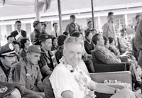 Henry Cabot Lodge, Jr., is wearing a lei. He is surrounded by many other military members and officers, from both the Vietnamese and American militaries.