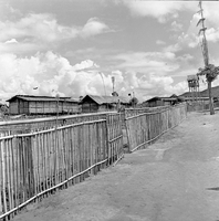 "Montagnards - Showplace Strat. Ham - 8-21-62 - In MTs - Faces - Blockhouses" A fence along the edge of a village.