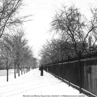 View lookng north of iron fence along R street around 1900. University Hall appears in the back, left, and the Chemistry Laboratory to the right. View Image