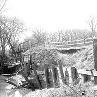 Original caption: Salt Creek bridge West of penitentiary showing damaged barricade and paving. Apr. 16, 1922
