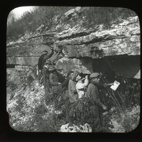 Original caption:  Ledge formerly quarried at Green's exposure in lower part of bluffs opp. So. Bend. NAB. Oct 21, 1911 Group of men viewing and stand beneath ledge. Cass County. (121111-00246)